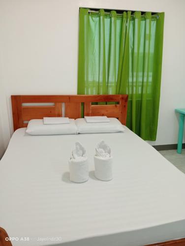a white bed with two tissue boxes on it at Lapyahan Guest House Room 5 in Lalao