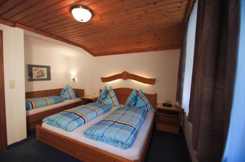 a bedroom with two beds and a wooden ceiling at Gästehaus Aigner in Saalbach-Hinterglemm