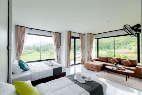 ein Schlafzimmer mit einem Bett und ein Wohnzimmer mit Fenstern in der Unterkunft Khaosok River Stone Resort & Camp in Ban Thung Lang Tham