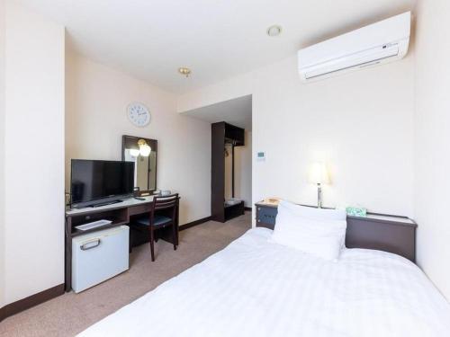 a bedroom with a bed and a desk with a television at Tabist Hotel New Osamura Sabae in Fukui