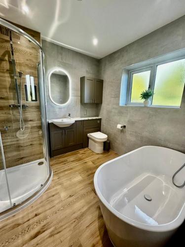 a bathroom with a tub and a shower and a toilet at Marzion House with Hot Tub in Tattershall Thorpe