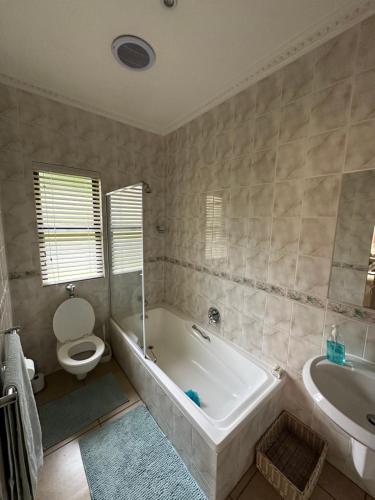 Un baño con bañera, inodoro y lavabo. en Clivia Guesthouse, en Pietermaritzburg