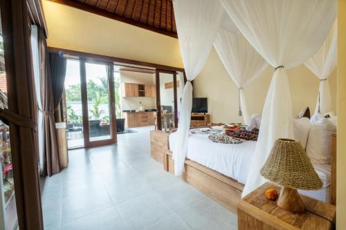 una camera da letto con un grande letto con tende bianche di Rama Ubud Villa ad Ubud