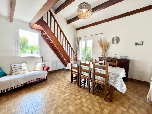 a living room with a table and chairs and a staircase at Maison familiale 3 chambres proche de la plage, jardin & tranquillité in Saint-Denis-dʼOléron