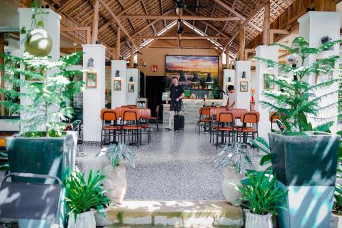 a person standing in a restaurant with chairs and a counter at Nam garden lodge in Tân Phú