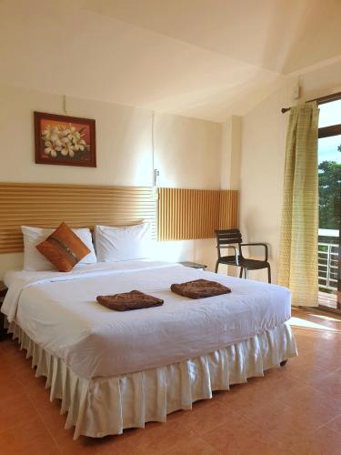 a bedroom with a large white bed with two towels on it at Penzy Guest House in Chaweng