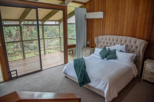 a bedroom with a large bed with white sheets and green pillows at Willow Lodge Retreat in Paringa