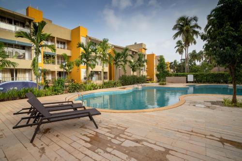 a bench next to a swimming pool in front of a building at Nayaab by Leo Homes - 2BHK Flat near Anjuna Beach in Anjuna