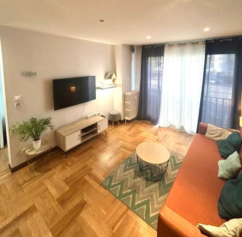 a living room with a couch and a flat screen tv at Bel appartement proche de toutes commodités in Grenoble
