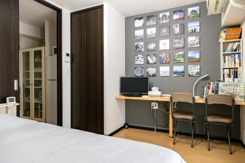 ein Schlafzimmer mit einem Bett und einem Schreibtisch mit Stühlen in der Unterkunft Hotel Small World in Hiroshima
