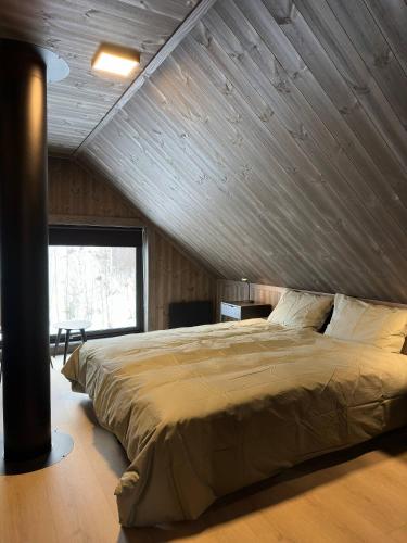 a large bed in a room with a wooden wall at Nice cabin at Norefjell skicenter in Noresund