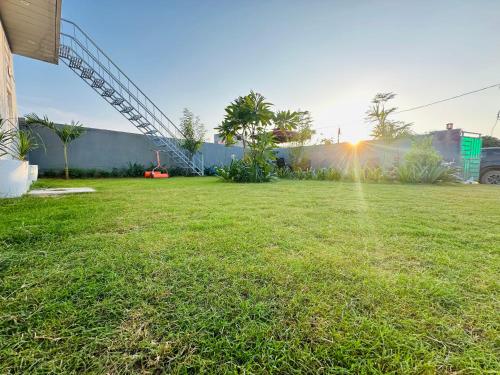 une cour herbeuse avec le soleil en arrière-plan dans l'établissement Ekant The Luxury Farm, à Jaipur