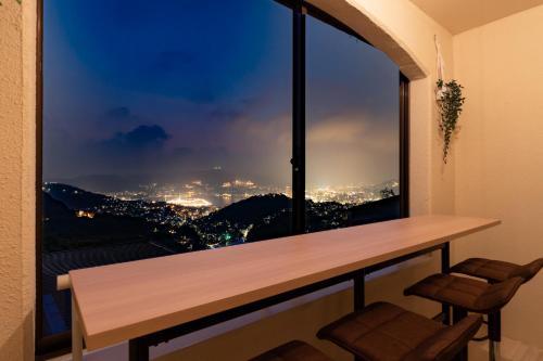 a room with a table and a window with a view at Nagasaki Night View Stay - 世界新三大夜景を望む宿 - Lotus長崎 in Nagasaki