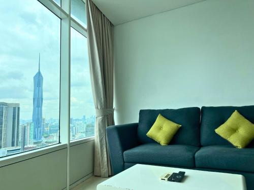 a living room with a blue couch and a large window at Vortex Apartments Kuala Lumpur in Kuala Lumpur