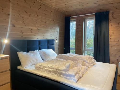 a bed in a room with a wooden wall at Moderne storhytte med 5 soverom og 3 bad in Beitostøl