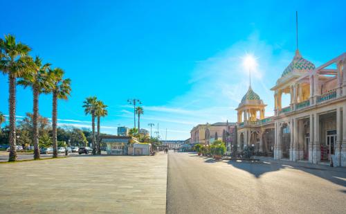 a city street with a building and palm trees at A-Mare in Viareggio