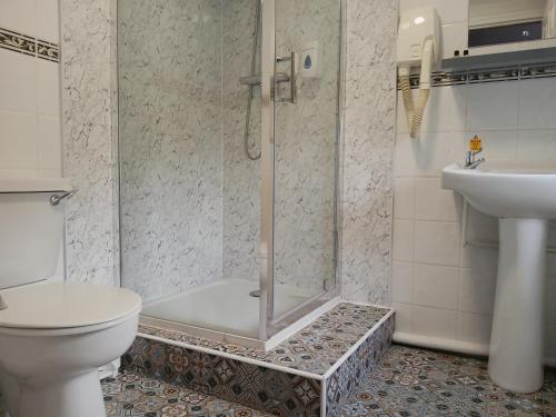 a bathroom with a shower and a toilet and a sink at The George Hotel, Dereham in East Dereham