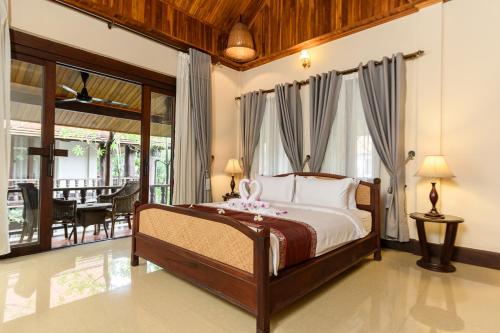 a bedroom with a large bed and a balcony at Treasure Heritage Hotel in Luang Prabang
