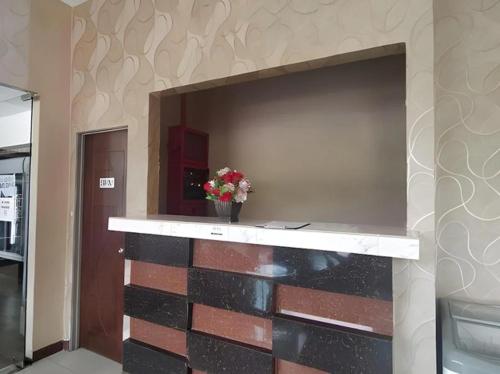 a wall with a fireplace with a vase of flowers at Get Inn Hotel in Gua Sai