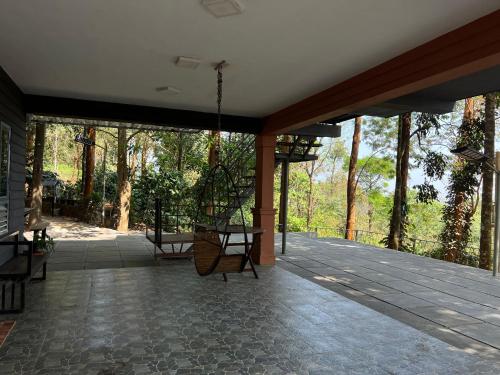 a screened in porch with a swing and trees at Wild root stay- Aster Chalet in Wayanad