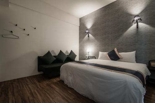 Una habitación de hotel con una cama grande y un sofá. en Norden Ruder Hostel Taitung, en Taitung