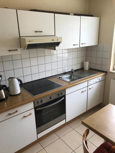 a kitchen with white cabinets and a sink at Kleymann RE26 in Sögel