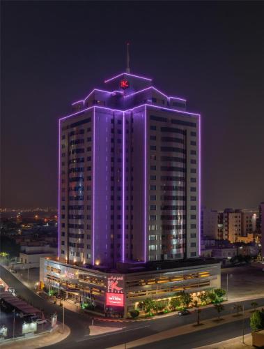 ein großes Gebäude mit violetten Lichtern in der Nacht in der Unterkunft The K Hotel, WorldHotels Distinctive in Manama