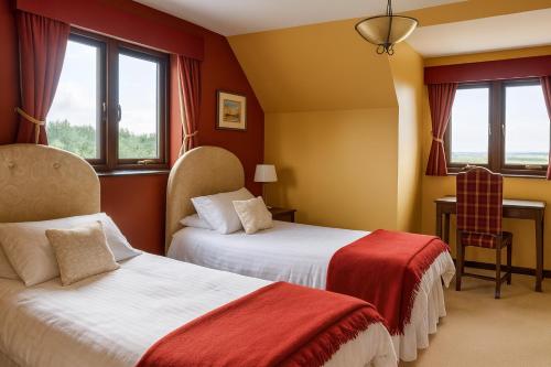 a hotel room with two beds and a chair at Ocean View Lodge in Kilchiaran
