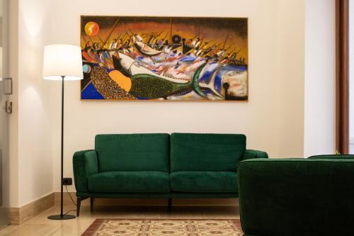 トラーパニにあるBADIA NUOVA Apart Hotelのリビングルーム(緑のソファ、絵画付)