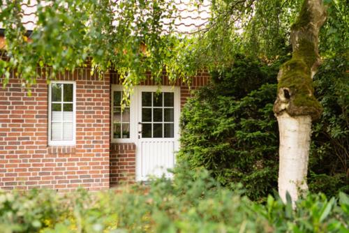 a brick house with a white door and a tree at Knipper RE24 in Sögel