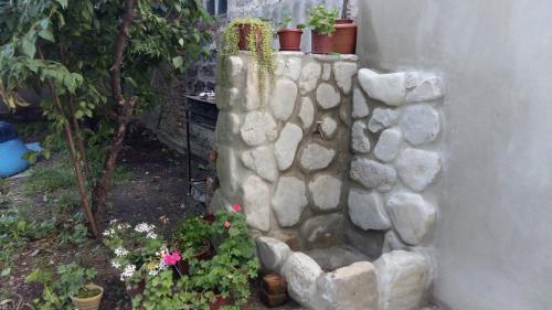 a stone wall with plants and flowers in a yard at Dima's Guesthouse in Tʼelavi