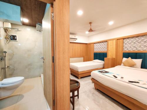 a bathroom with two beds and a toilet and a sink at Hotel Aishwarya Residency in Nerul