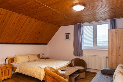 a bedroom with a bed and a couch and a window at Penzion JAS in Zuberec