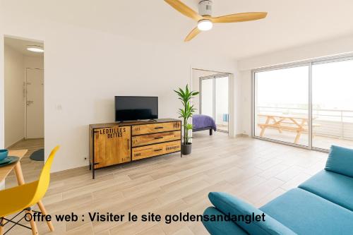 a living room with a tv and a blue couch at Golden Sand Anglet Biarritz - Front de mer - Parking Privatif Gratuit in Anglet