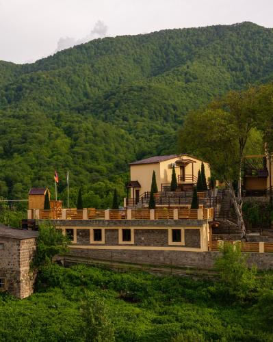 a building with a mountain in the background at DiliVita Rest House in Dilijan
