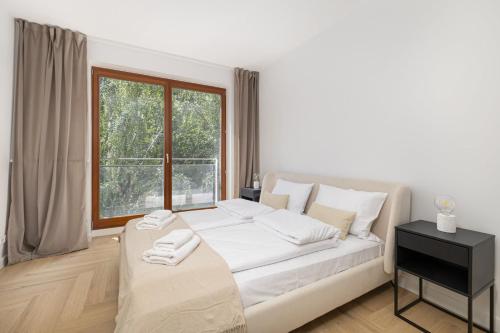 a bedroom with a bed with white sheets and a window at Luxurious Apartment with a Terrace and Garage - Grzybowska in Warsaw