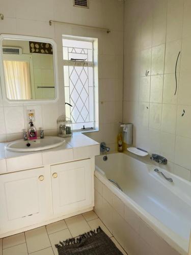 a bathroom with a tub and a sink and a mirror at Amanzi Lodge in Greytown