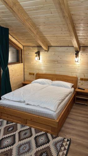 a bedroom with a bed in a wooden room at Pensiunea Plaiul Bucovinei in Şarul Dornei