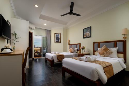 a hotel room with two beds and a balcony at Grand Bayon Siem Reap Hotel in Siem Reap