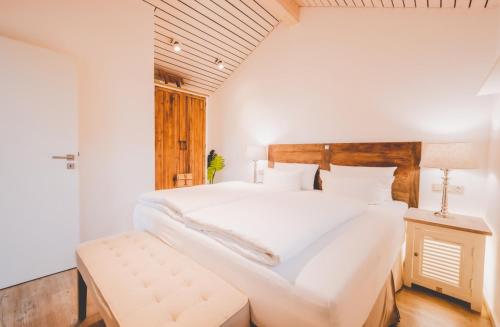 a bedroom with a large white bed with a wooden headboard at Marienhöh - Hideaway & Spa in Langweiler