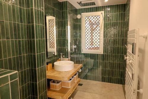 a green tiled bathroom with a sink and a mirror at Casetta Mare di Cala Rossa in Cala Rossa