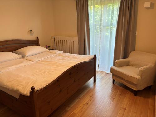 a bedroom with a bed and a chair and a window at Apartma Lesjak - pobeg v naravo 2 in Šmihel nad Mozirjem