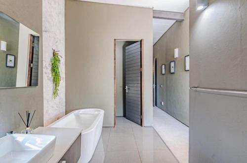 un bagno bianco con vasca e lavandino di Luxury Smart 3bed Home a Pretoria