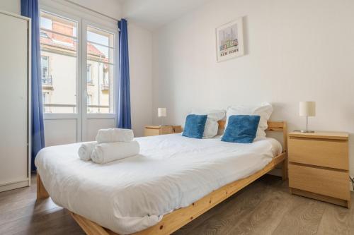 Un dormitorio con una gran cama blanca con almohadas azules. en Hortensia - Pause nancéienne, en Vandoeuvre-lès-Nancy