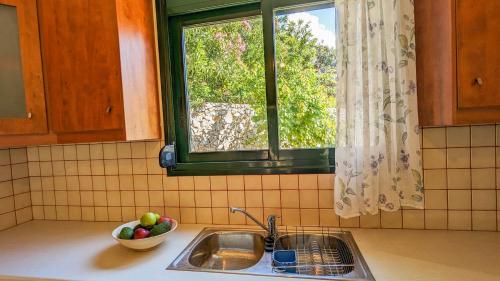 - un évier de cuisine avec un bol de fruits et une fenêtre dans l'établissement Villa Phoebe, à Kefalás