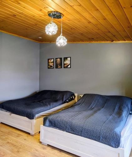 two beds in a room with wooden ceilings at Apartamenty Jodłowa in Suwałki