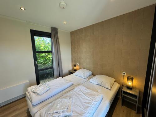 a bedroom with two beds and a window at Enkhuizer Strand Chalet Strandjuwel Erste Reihe Hausnr 205 in Enkhuizen