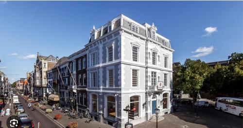 een wit gebouw aan de kant van een stadsstraat bij ADAM & EVE Paleisstraat in Den Haag