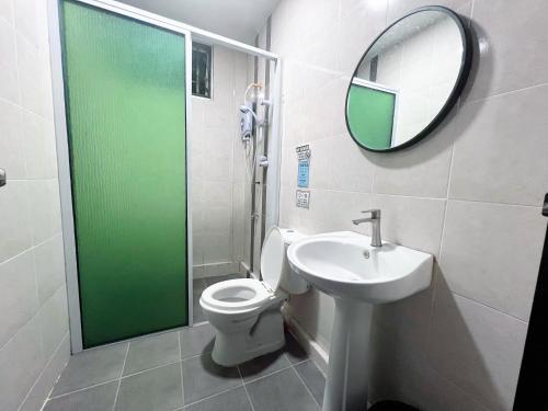 a bathroom with a toilet and a sink and a mirror at Kelly Homestay in Sibu