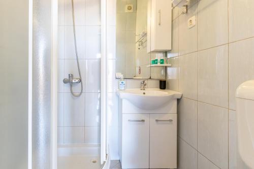 Un baño blanco con ducha y lavabo. en Apartments Danka with Shared Pool, en Pula
